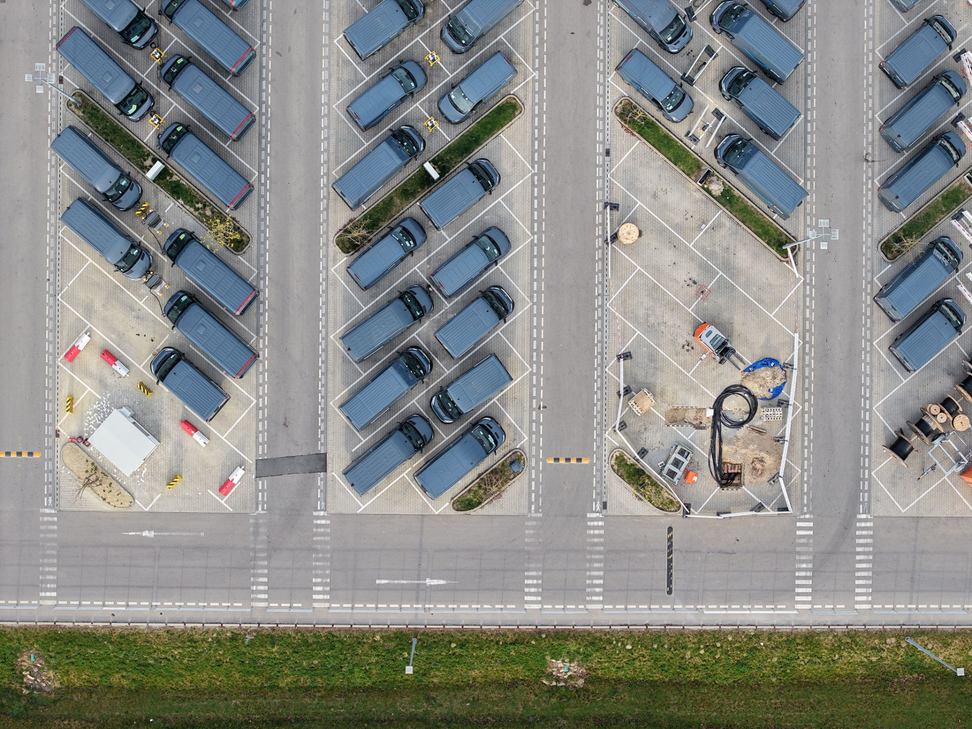 Luftaufnahme eines Parkplatzes mit verlegten Kabeln und Ladesäulenfundamenten